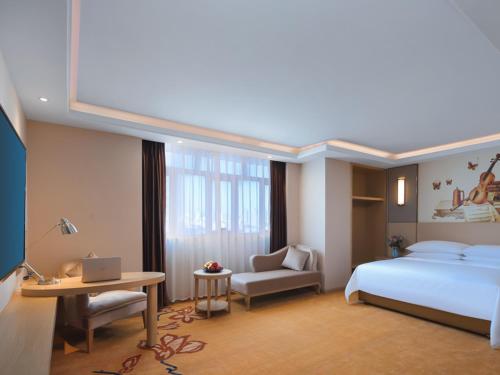 a hotel room with a bed and a desk with a laptop at Vienna International Hotel FuJian PuTian Pearl in Putian
