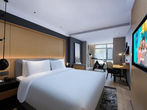 a hotel room with a large white bed and a desk at Park Inn by Radisson Shandong Yucheng High-tech Zone Detpak Plaza in Yucheng