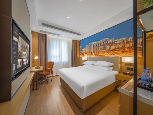 a bedroom with a bed and a painting of a city at Vienna International Hotel Kunming longquan road Finance University in Kunming