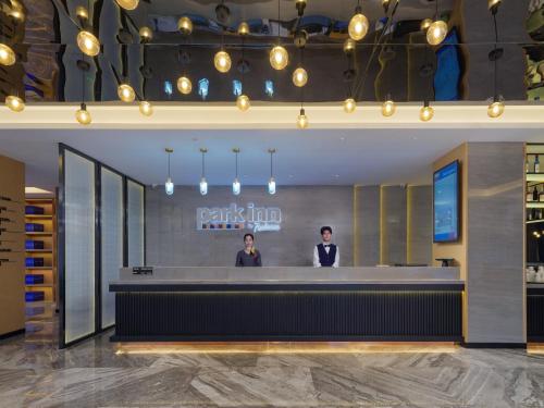 two men standing at the counter of a restaurant at Park Inn by Radisson Shandong Yucheng High-tech Zone Detpak Plaza in Yucheng