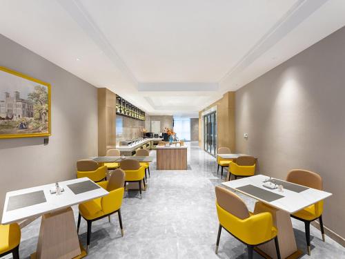 a dining room with tables and yellow chairs at Vienna International Hotel Linqu Wanda Plaza in Weifang