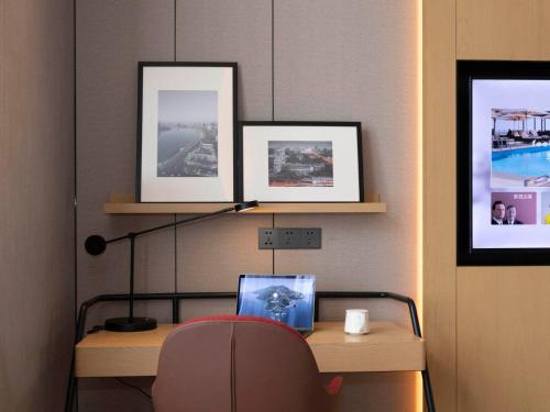 a desk with a computer and three pictures on a wall at Park Inn by Radisson Jilin Beishan Park&Songhua River in Jilin