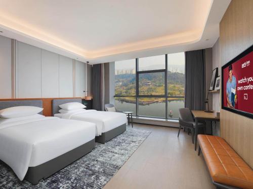 a hotel room with two beds and a tv at Park Inn by Radisson Nanchong Yilong Star City Plaza in Yilong