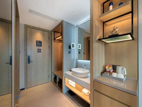 een badkamer met een wastafel en een spiegel bij Park Inn by Radisson Chengdu Sihe Metro Station Xinchuan in Chengdu