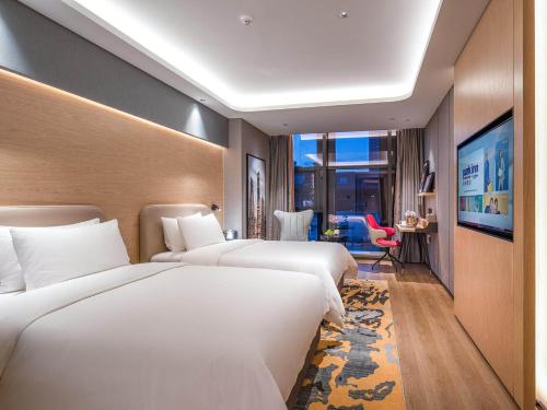 a hotel room with two beds and a large window at Park Inn by Radisson Tongling The City Core in Tongling