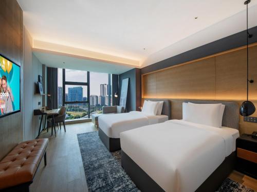 成都市にあるPark Inn by Radisson Chengdu Sihe Metro Station Xinchuanのベッド2台とデスクが備わるホテルルームです。