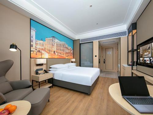 成都市にあるVienna International Hotel Chengdu Shuangliu Airport Terminal Beijing Hualianの大きなベッドとノートパソコンが備わるホテルルームです。