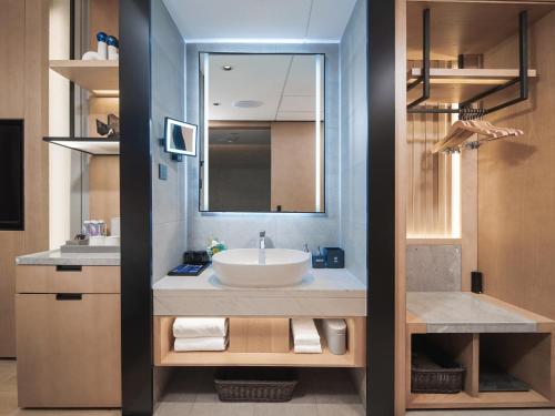 a bathroom with a sink and a mirror at Park Inn by Radisson Tianjin Five Old Street Nanjing Road in Tianjin