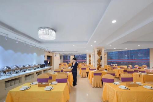 a person standing in a room with tables and chairs at Vienna International Hotel FuJian PuTian Pearl in Putian