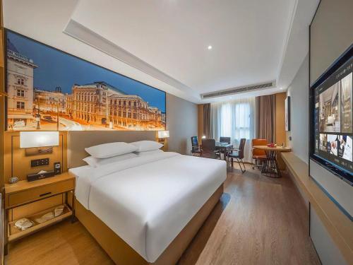 a hotel room with a large bed and a flat screen tv at Vienna International Hotel Kunming longquan road Finance University in Kunming