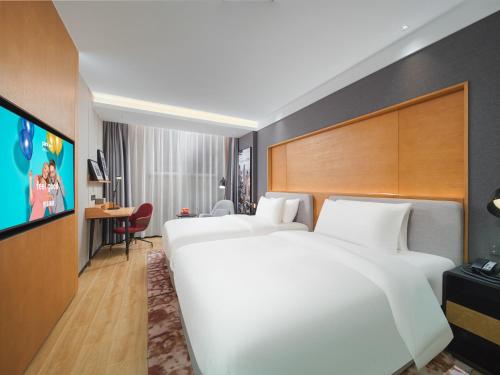 a hotel room with two beds and a flat screen tv at Park Inn by Radisson Tianjin Five Old Street Nanjing Road in Tianjin