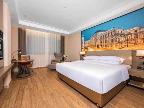 a large white bed in a hotel room with a painting at Vienna International Hotel Xianyang International Airport Hotel in Xianyang