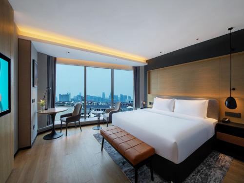 a hotel room with a large white bed and a desk at Park Inn by Radisson Shaoxing China Keqiao in Shaoxing