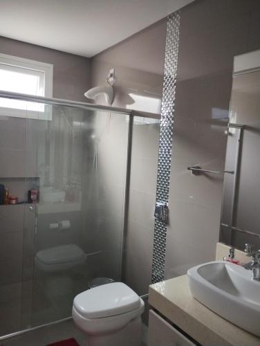 y baño con ducha, aseo y lavamanos. en Ótimo quarto, requinte., en Rio do Sul