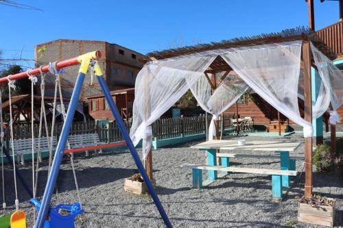 a playground with a picnic table and a swing set at Cabañas Caudiel in Caudiel