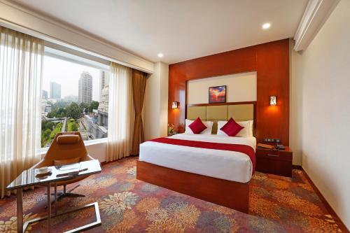 a hotel room with a bed and a large window at KINGSTON HOTEL in Bangalore