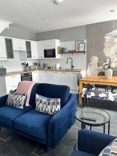 a living room with a blue couch and a kitchen at Isfryn, holiday home in Aberdyfi in Aberdyfi
