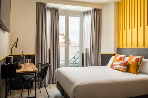 a hotel room with a bed and a table and a window at BYPILLOW Crosstown in Madrid