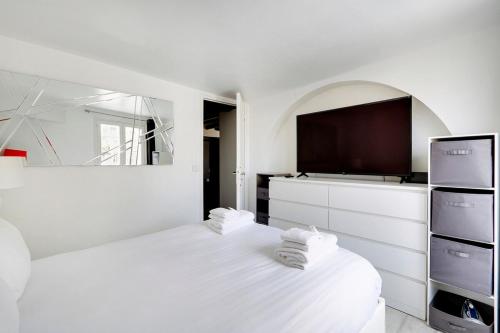 une chambre blanche avec un lit et une télévision à écran plat dans l'établissement Paris Marais Beaubourg Area, à Paris