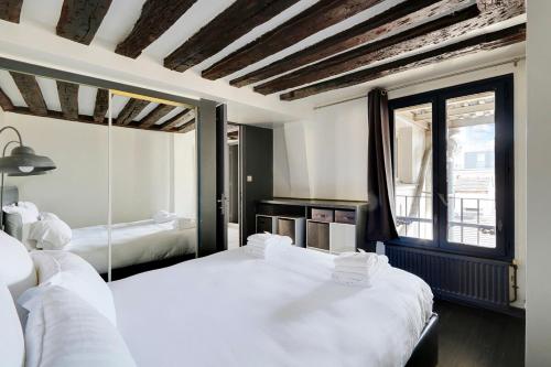 1 Schlafzimmer mit 2 Betten und einem großen Fenster in der Unterkunft Paris Marais Best WE MERRIS in Paris