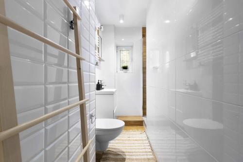 a white bathroom with a toilet and a sink at Elite Apartments Cozy Studio Sopot in Sopot