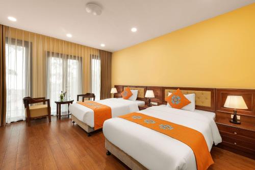 two beds in a hotel room with yellow walls at Sapa Convention Center (Green Forest Hotel) in Sa Pa