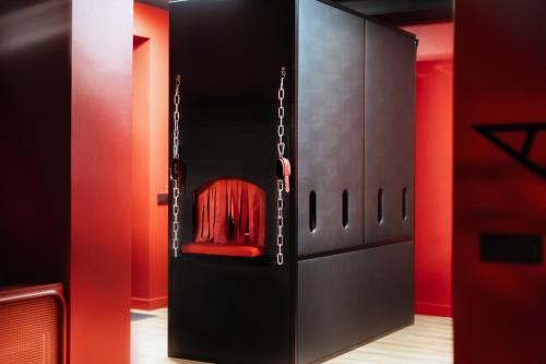 a black cabinet with a red chair in it at BDSM Red Apartments in Vilnius