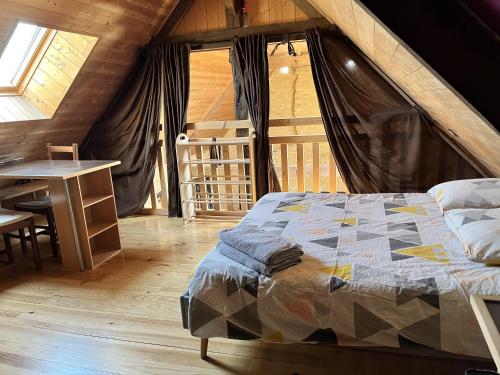 um quarto com uma cama e uma mesa num sótão em Un grand Paradis dans le Périgord em Saint-Amand-de-Coly