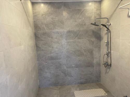 y baño con ducha y pared de piedra. en منتجع ريتام, en Al-Hasa