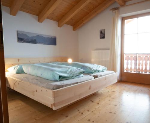 ein Holzbett in einem Zimmer mit einem großen Fenster in der Unterkunft Biohof Unterstein in Ulten