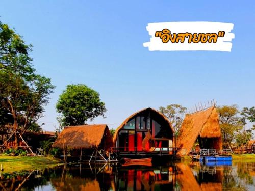 a house with a thatched roof on a body of water at บ้านนกฮูก อิงสายชล in Ban Khlong Sai