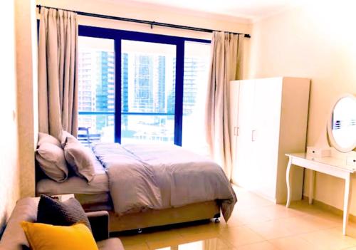 a bedroom with a bed and a large window at Lake View Studio Cluster X JLT - 7min to metro near marina in Dubai