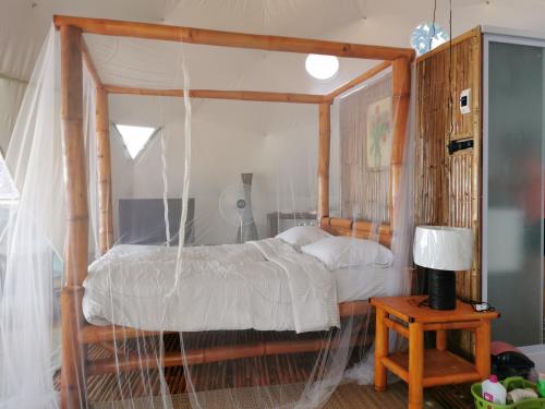 a bedroom with a wooden canopy bed with a table at Glamping Dome Dauin Beach and Dive Resort in Dauin