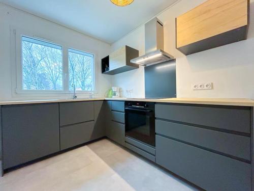 - une cuisine avec des placards gris et une cuisinière dans l'établissement La Baugerie enchantée, à Saint-Sébastien-sur-Loire