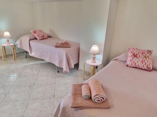 a room with two beds with pink sheets and towels at Villa Maddalena guest house in Sorso