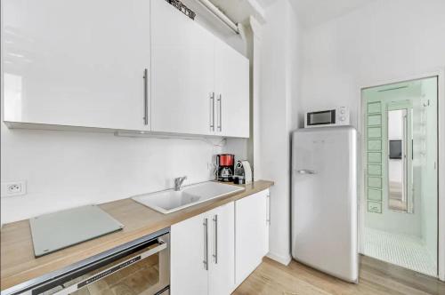 a white kitchen with a sink and a refrigerator at Le Vendôme - Moderne & Elégant - Business in Paris