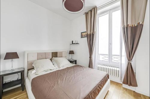 a white bedroom with a bed and a large window at Le Vendôme - Moderne & Elégant - Business in Paris
