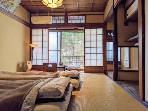 a room with four beds in a room with windows at Guesthouse Itoya Kyoto in Kyoto