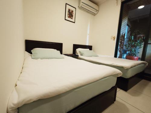 two twin beds in a room with a window at Cat5 Mewo Meow House in Taipei