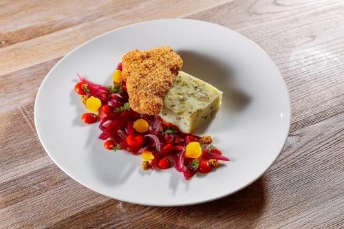 a white plate with a piece of cheese and vegetables at Lumen Gasztropanzió in Eger
