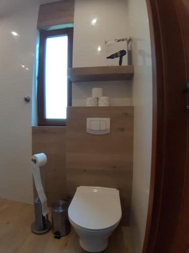 łazienka z białą toaletą i oknem w obiekcie Domki Wypoczynkowe Zadzielanka w Żywcu