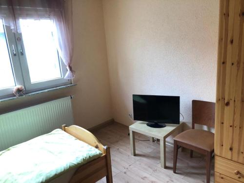 Habitación pequeña con cama y TV. en Monteurunterkunft Oberhausen-Rheinhausen, en Oberhausen-Rheinhausen