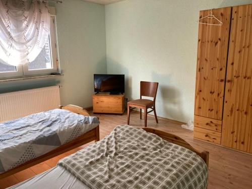 - une chambre avec un lit, une chaise et une télévision dans l'établissement Monteurunterkunft Oberhausen-Rheinhausen, à Oberhausen-Rheinhausen