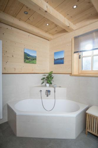 a large white bath tub in a room with wooden walls at Ferienwohnung Tegernsee,Fam Schneider, Kreuth-Grüneck in Kreuth