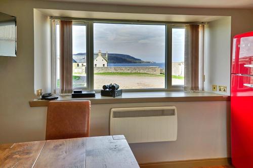 uma janela com vista para o oceano e uma mesa em Balnakeil Cattleman's Bothy em Durness