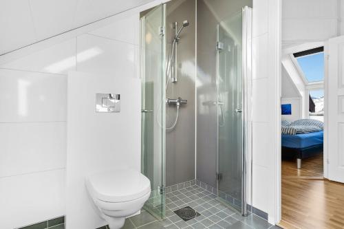 uma casa de banho branca com um chuveiro e um WC. em Nappstraumen Seafront Cabin, Lilleeid 68 em Gravdal
