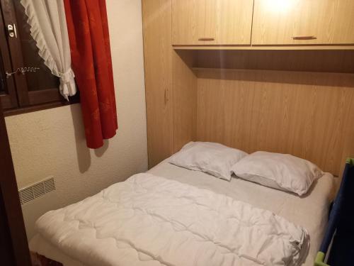 - un lit avec deux oreillers dans une petite chambre dans l'établissement La Montagne, à Le Biot