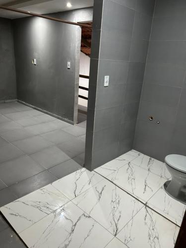 ein Badezimmer mit weißem Marmorboden und einer Toilette in der Unterkunft Recanto do jao in Maragogi