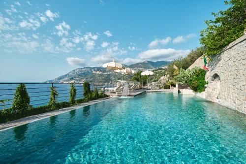 una piscina de agua azul frente al océano en Hotel Botanico San Lazzaro en Maiori