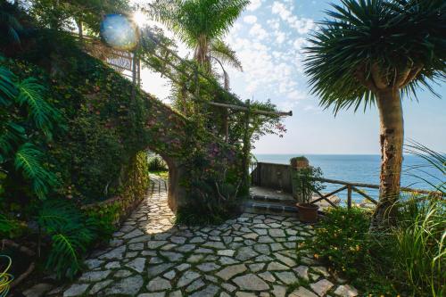 a stone pathway leading to the ocean with a palm tree at Hotel Botanico San Lazzaro in Maiori